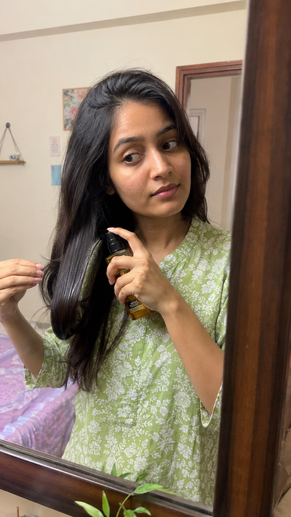 Indian woman applying hair serum in front of mirror